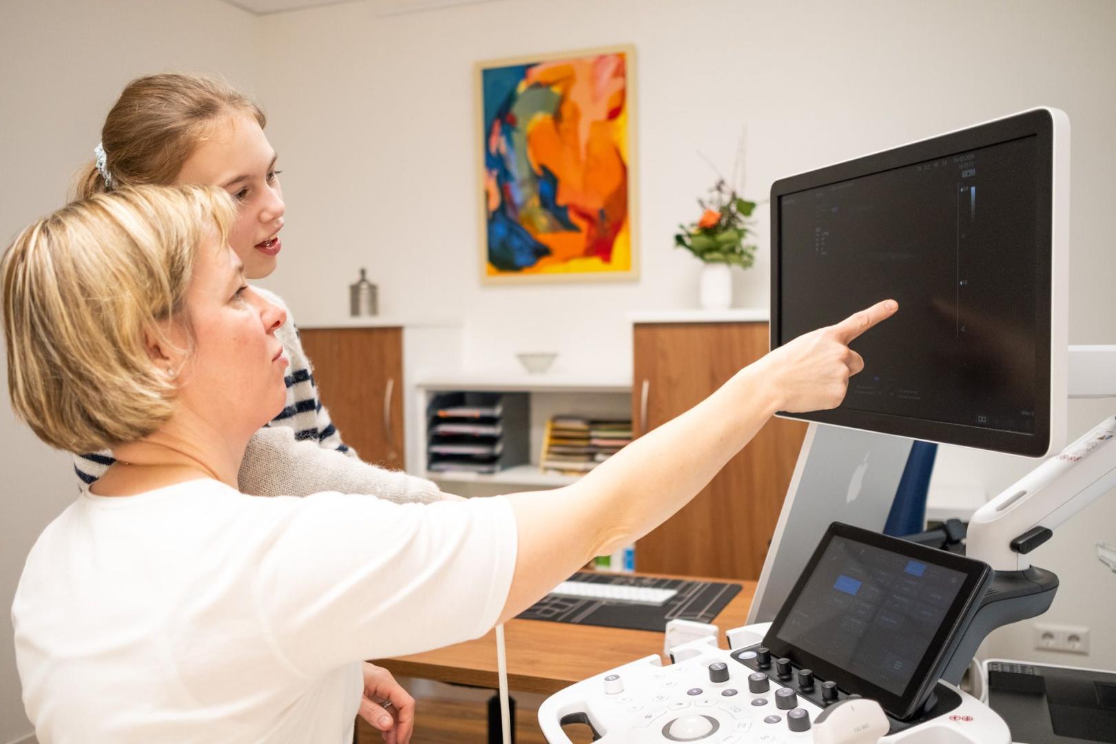 Ärztin erklärt einer Patientin die Untersuchung am Sonografiegerät Ärztin erklärt einer Patientin die Untersuchung am Sonografiegerät