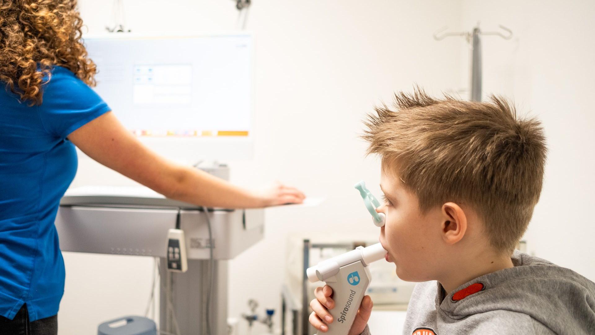 Arzthelferin führt bei einem Jungen eine Spirometrie-Untersuchung durch